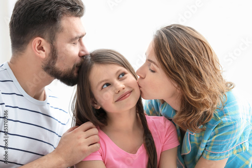 Morning of happy parents with little daughter in bedroom