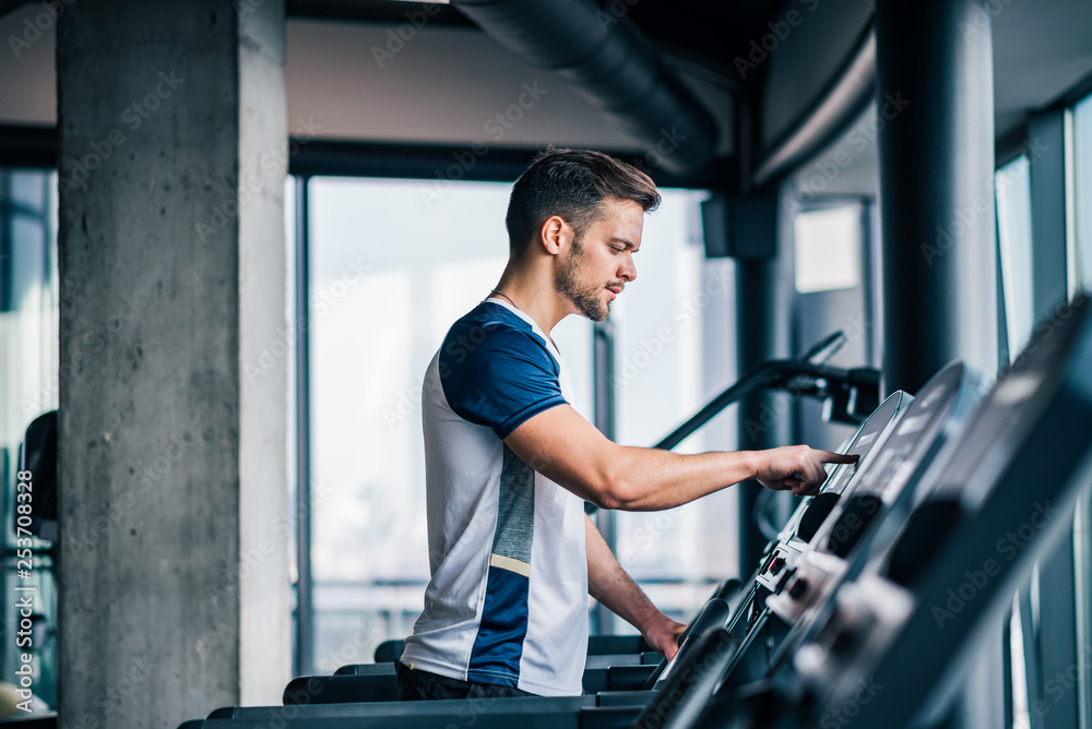 Side view of athlete adjusting speed on treadmill, doing cardio workout in the gym. Side view of athlete adjusting speed on treadmill, doing cardio workout in the gym.