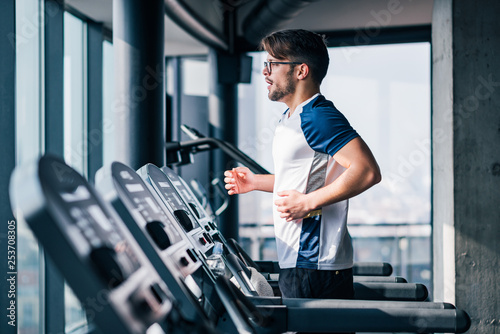 Side view of man running in modern gym with a view.