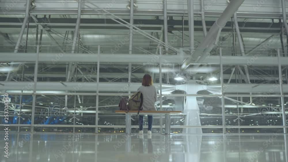 Happy Asian woman looking around sitting on chair in terminal hall while waiting her flight at the departure gate in international airport. Lifestyle women happy in airport concept. Happy Asian woman looking around sitting on chair in terminal hall while waiting her flight at the departure gate in international airport. Lifestyle women happy in airport concept.