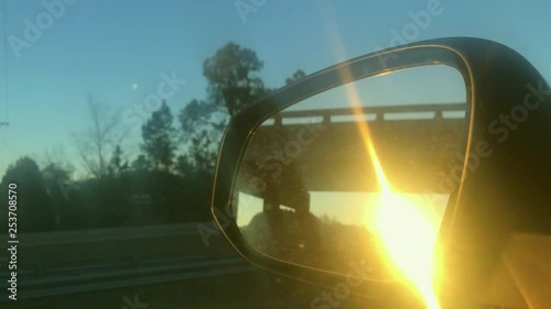 sunset in the rear view mirror of a rav4 car cruising on a clean highway photo