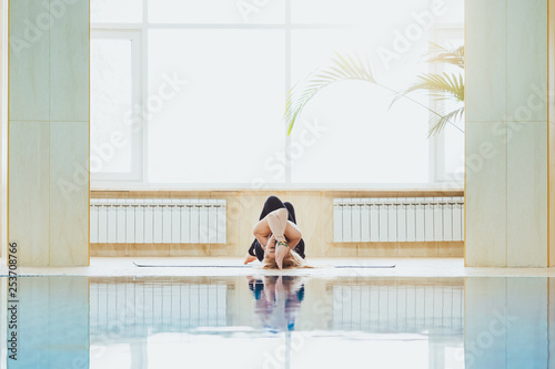 Beautiful attractive woman practice yoga pose in the gym pool in the morning, relax in holiday or day off. Healthy lifestyle