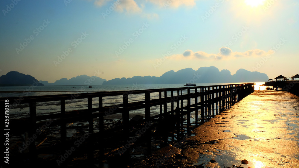 Silhouette abandoned old pier to the sea with sunrise sky.