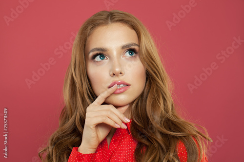 Young beautiful woman thinking and looking up over pink background