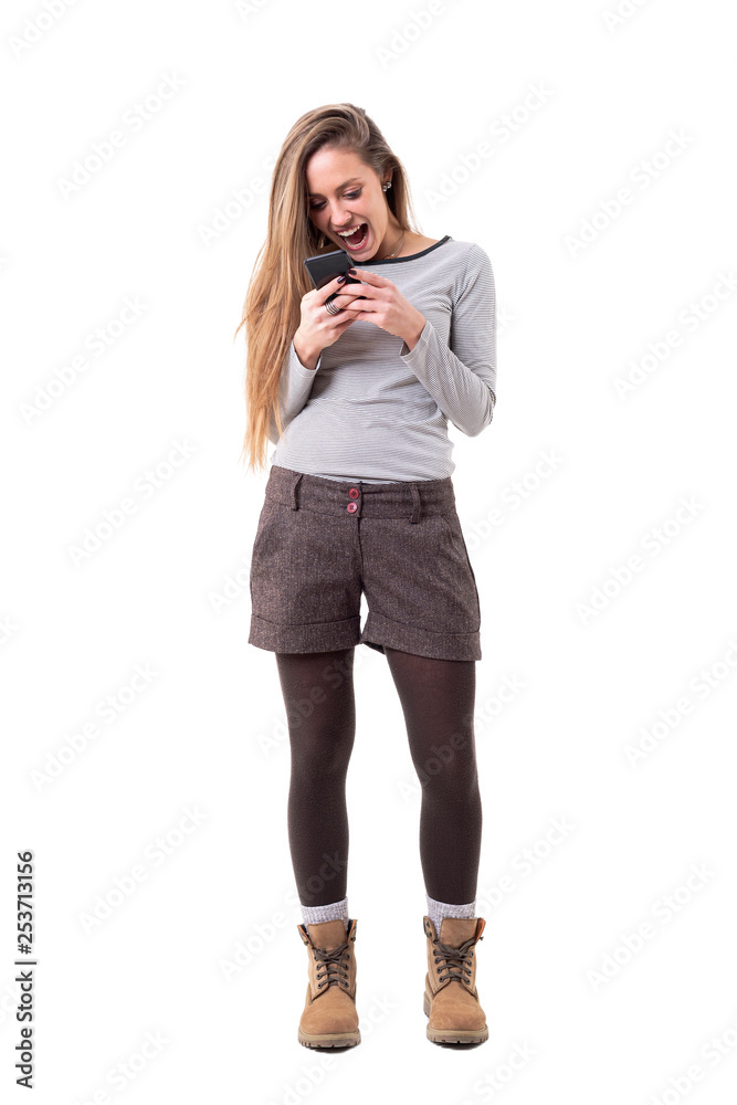 Overjoyed young stylish woman screaming while reading and holding mobile phone. Full body isolated on white background. Overjoyed young stylish woman screaming while reading and holding mobile phone. Full body isolated on white background.