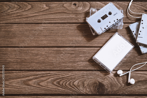Overhead shot of retro old audio cassette tape with earphone on vintage retro wooden background, flat lay top view with copy space.