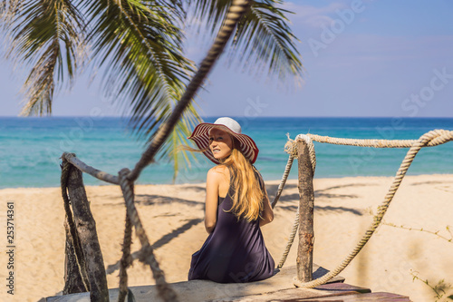 Vacation on tropical island. Woman in hat enjoying sea view from wooden bridge © galitskaya