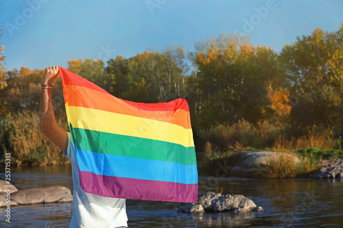 Man with rainbow LGBT flag outdoors, space for text. Gay symbol