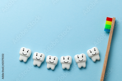 Healthy white teeth are smiling on blue background with toothbrush. Copy space for text.