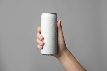 Woman holding aluminum can with beverage on grey background, closeup. Space for design