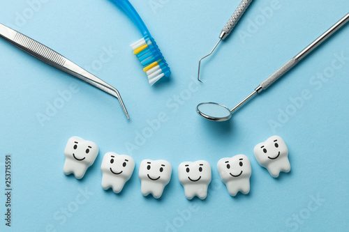 Healthy white teeth are smiling on blue background and dentist tools mirror, hook.