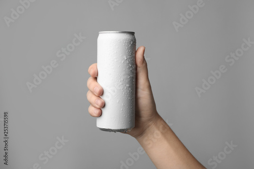 Woman holding aluminum can with beverage on grey background, closeup. Space for design