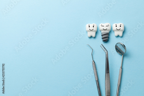 Healthy white teeth and implants are smiling on blue background and dentist tools mirror, hook. Copy space for text. photo