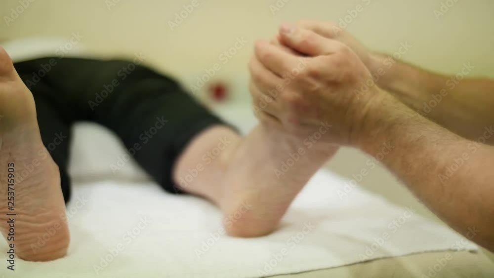 Physiotherapist massaging patient foot. Dolly shot