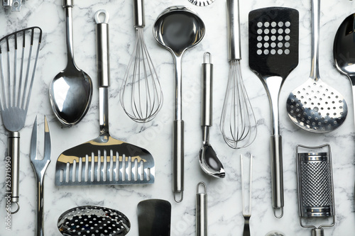 Different kitchen utensils on marble background, flat lay photo