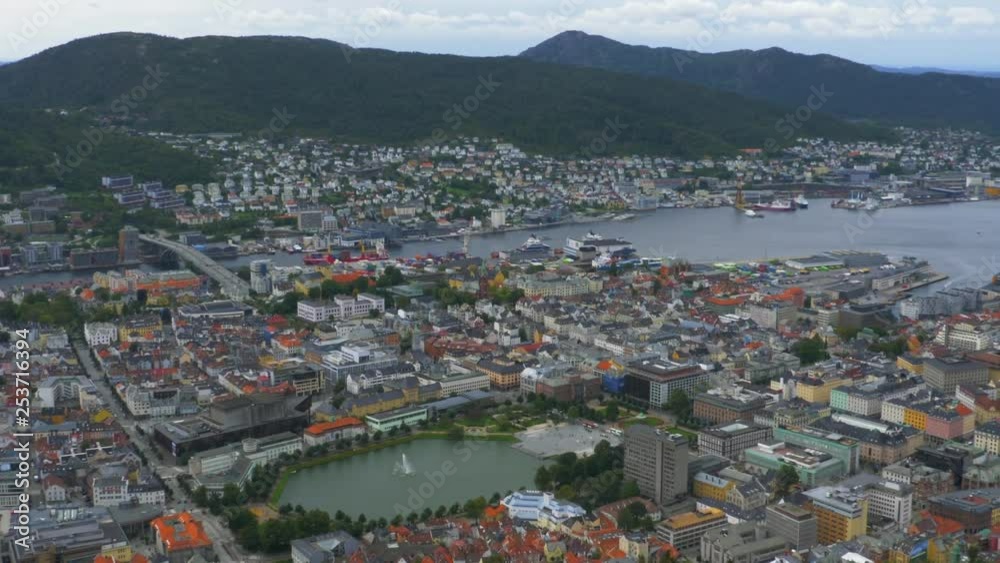 Wide, high view of Bergen, Norway from a nearby mountaintop overlooking the city, fjord, buildings and boats. Bergen is a city on southwestern coast of Norway surrounded by mountains and fjords. PAN.