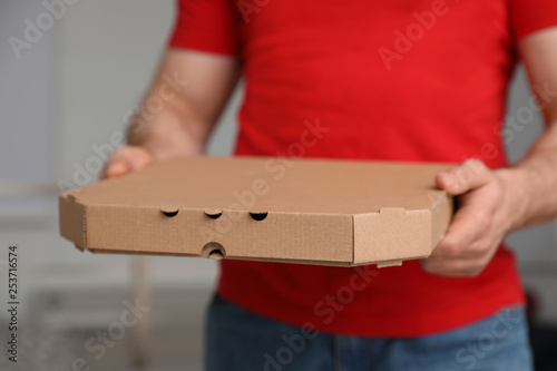 Courier with pizza box on blurred background, closeup © New Africa