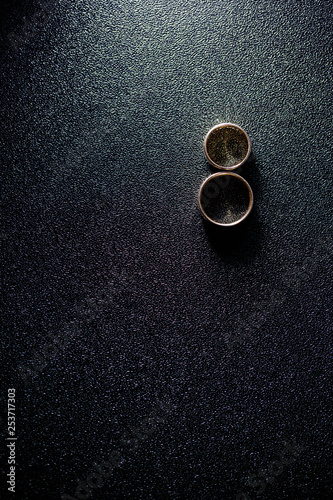golden wedding rings newlyweds lie on a black textural background