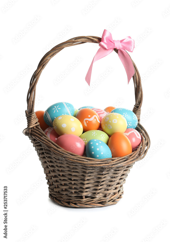 Wicker basket with painted Easter eggs on white background