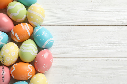 Many colorful painted Easter eggs on wooden background, top view. Space for text