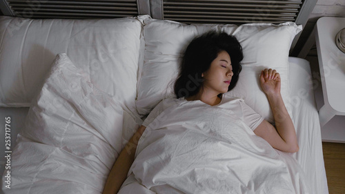 top view young attractive woman lying in bed sleeping resting at hotel enjoy comfortable soft cotton linen fresh bedding dreaming feels good. asian girl close eyes sleep well at night early morning