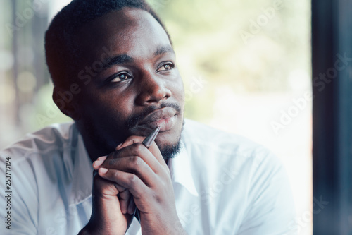 African man thinking and looking with holding a pen.