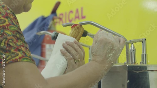 A woman stuffing farturas (portuguese name of a cultural food) in deep oil at Portugal summer village festivals photo