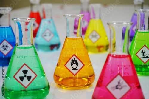 Many of Erlenmeyer flask with colorful solution and Variety type of chemical hazard warning symbols labels. Focus on Oxidizing sign,symbol. photo