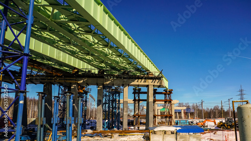The construction of the overpass over the functioning railway. Temporary metal structures are gradually replaced by reinforced concrete pillars