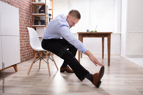 Businessman Stretching His Leg And Hand In Office
