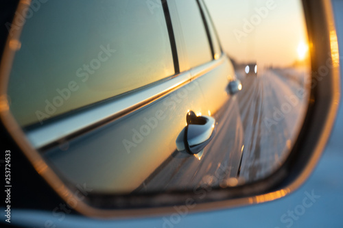 The winter road is reflected in the car's rear-view mirror. Sunset in winter. © Ирина Швейн