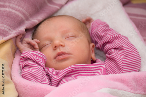 Neugeborenes Mädchen im pink gestreiften Body schläft