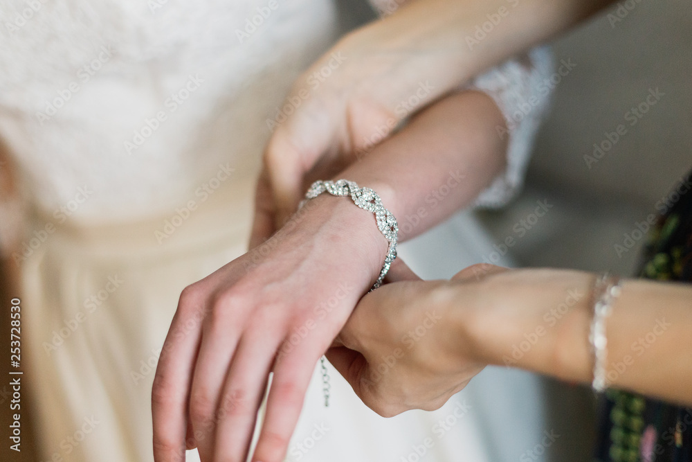 bride putting on luxury bracelet on hand in the morning, getting ready.