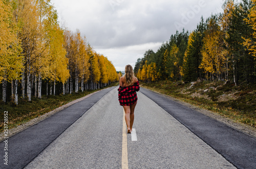 Young woman is walking on a lonely road in Lapland