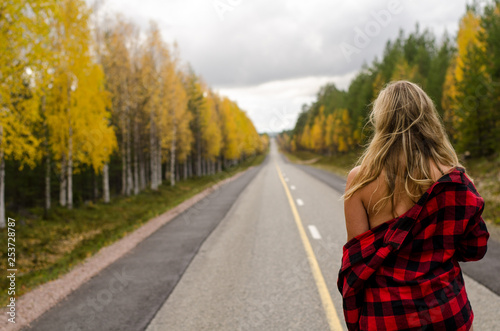 Young woman is walking on a lonely road in Lapland