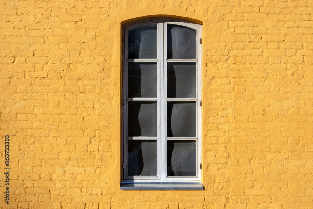 window on yellow painted brick wall
