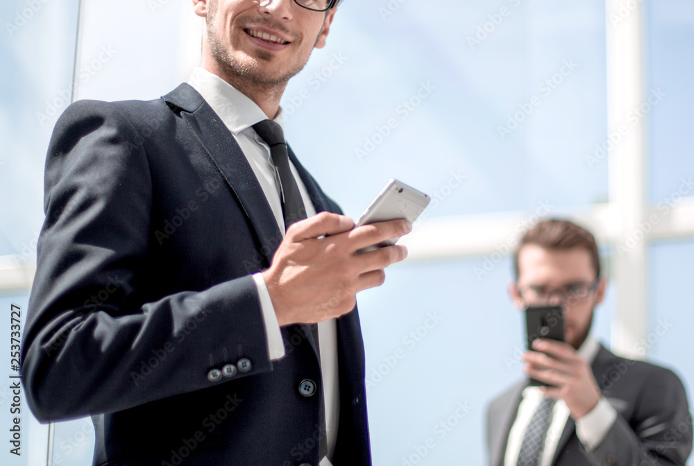 modern businessman with a smartphone on background office modern businessman with a smartphone on background office
