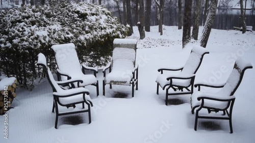 5 lawn chairs in the snow in the backyard, slow motion snowing photo