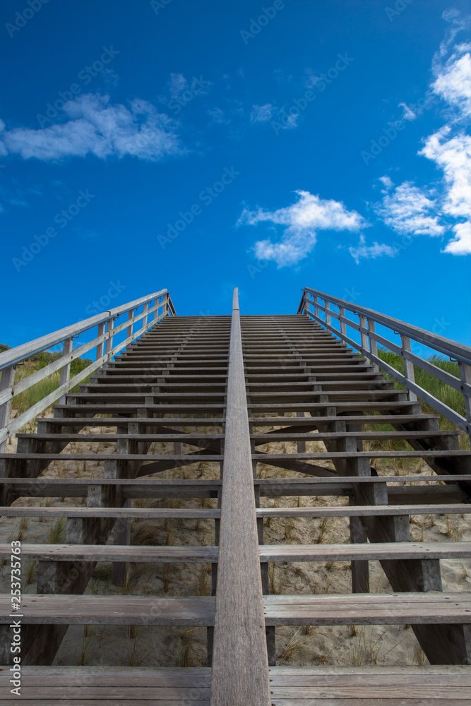 Treppe zum Strand ohne Menschen. Aufstieg mit Blick in den blauen Himmel Treppe zum Strand ohne Menschen. Aufstieg mit Blick in den blauen Himmel