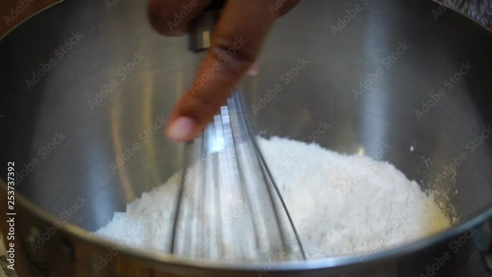 Close Up of Hand whisking flour mixture in metal mixing bowl, SLOWMO Close Up of Hand whisking flour mixture in metal mixing bowl, SLOWMO