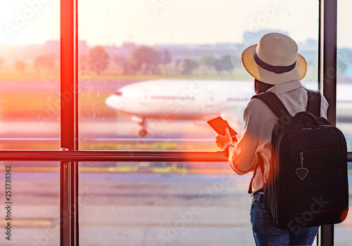 Woman holding passport waiting in transit area in the airport, standing by for the next schedule traveling, late delay of the arrival departure, missing checking in the boarding pass