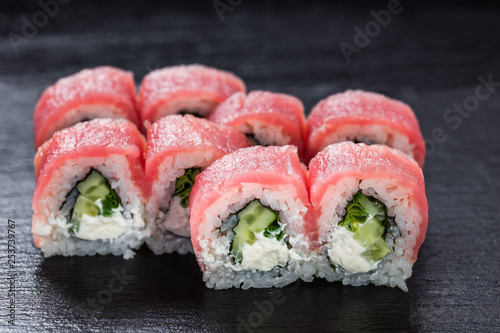Philadelphia makizushi roll with tuna arranged on stone background