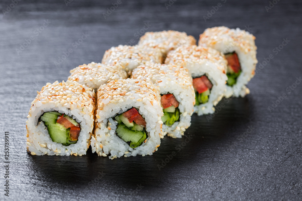 Vegeterian makizushi roll with cucumber and tomato over slate plate background