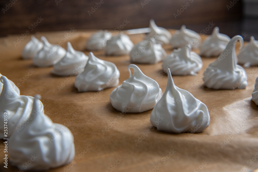 Closeup on raw meringue cookies on brown baking paper detailed Closeup on raw meringue cookies on brown baking paper detailed