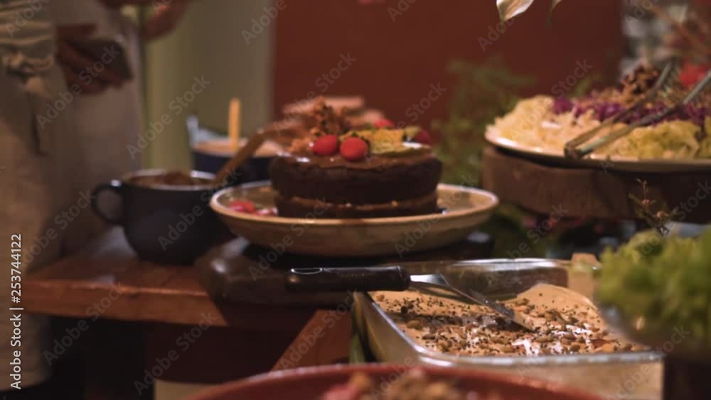 tilt shot of people serving vegan food on a dinner under candlelight tilt shot of people serving vegan food on a dinner under candlelight