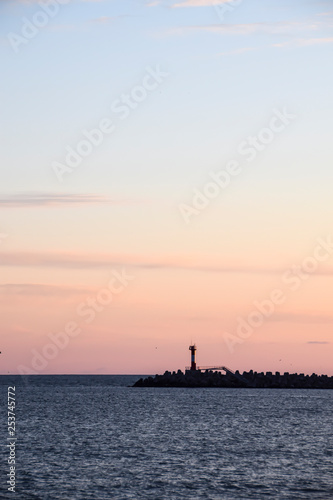 lighthouse silhouette and setting sun sunset red sky clouds © yalo173