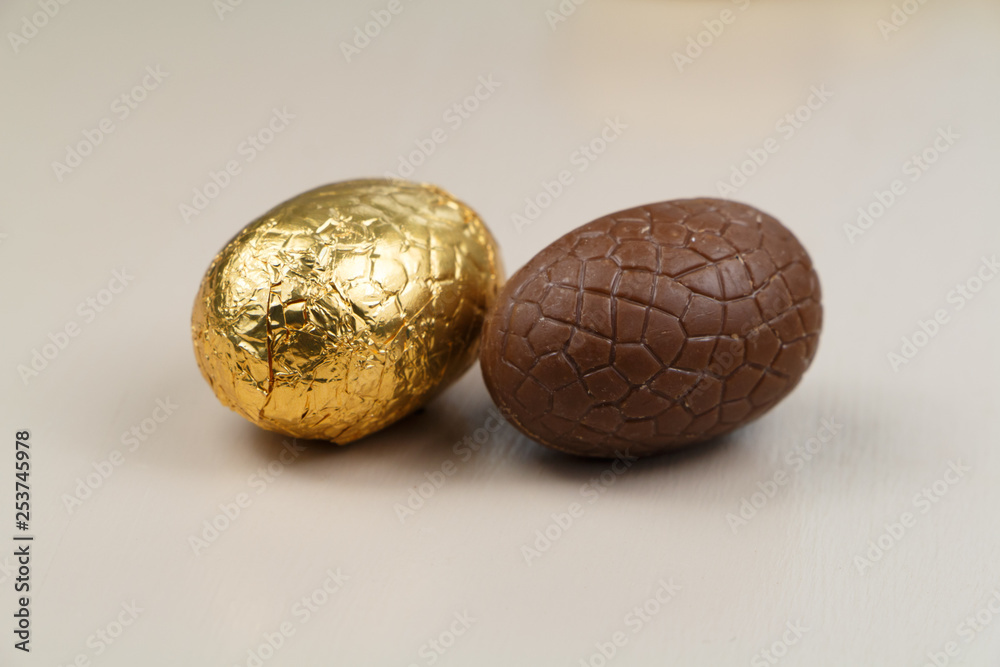 Two chocolate eggs with and without golden paper for Easter Two chocolate eggs with and without golden paper for Easter