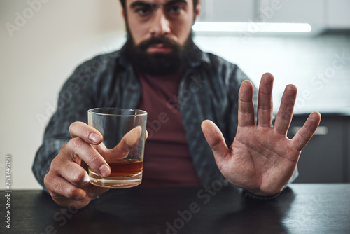 I am more afraid of alcohol than of all the bullets of the enemy. Addicted man refuses to drink a glass of whiskey. Cropped image. Selective focus