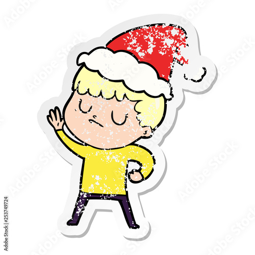 distressed sticker cartoon of a grumpy boy wearing santa hat