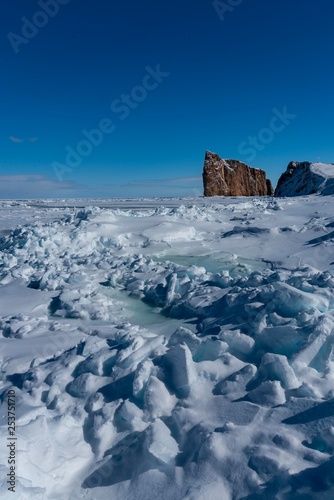 Coastal sea ice with the  Percé Rock in the background on a sunny winter afternoon. © Denis Comeau